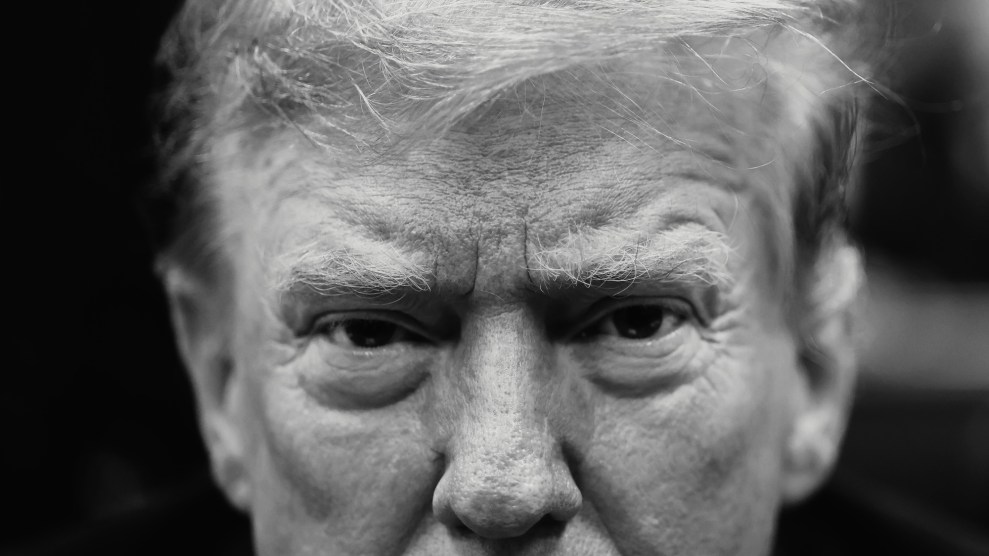 A black-and-white tightly cropped portrait of Donald Trump. With furrowed brow, Trump's stares directly into the camera lens.