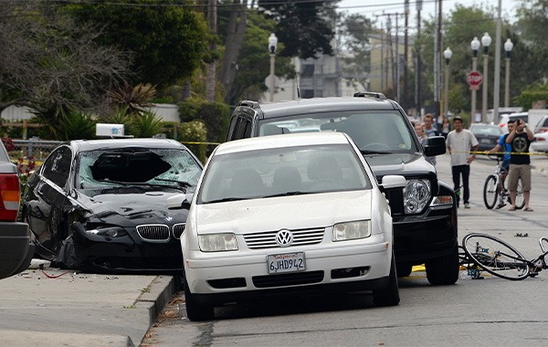 A white car sits in front of a crashed black sedan and a black SUV