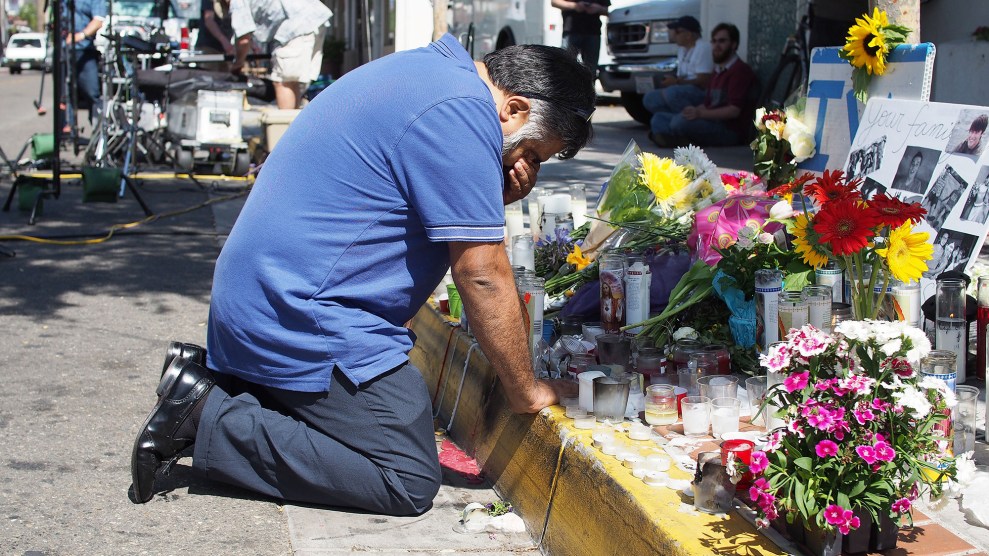 Man kneeling in front of memorial with flowers.