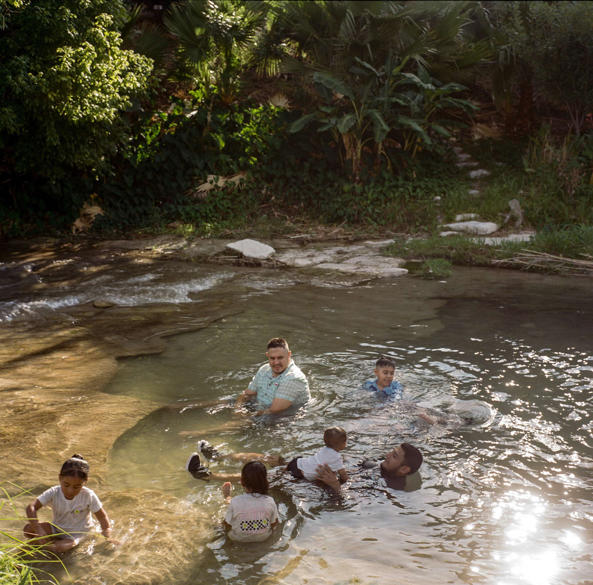Group of people wading in a creek.