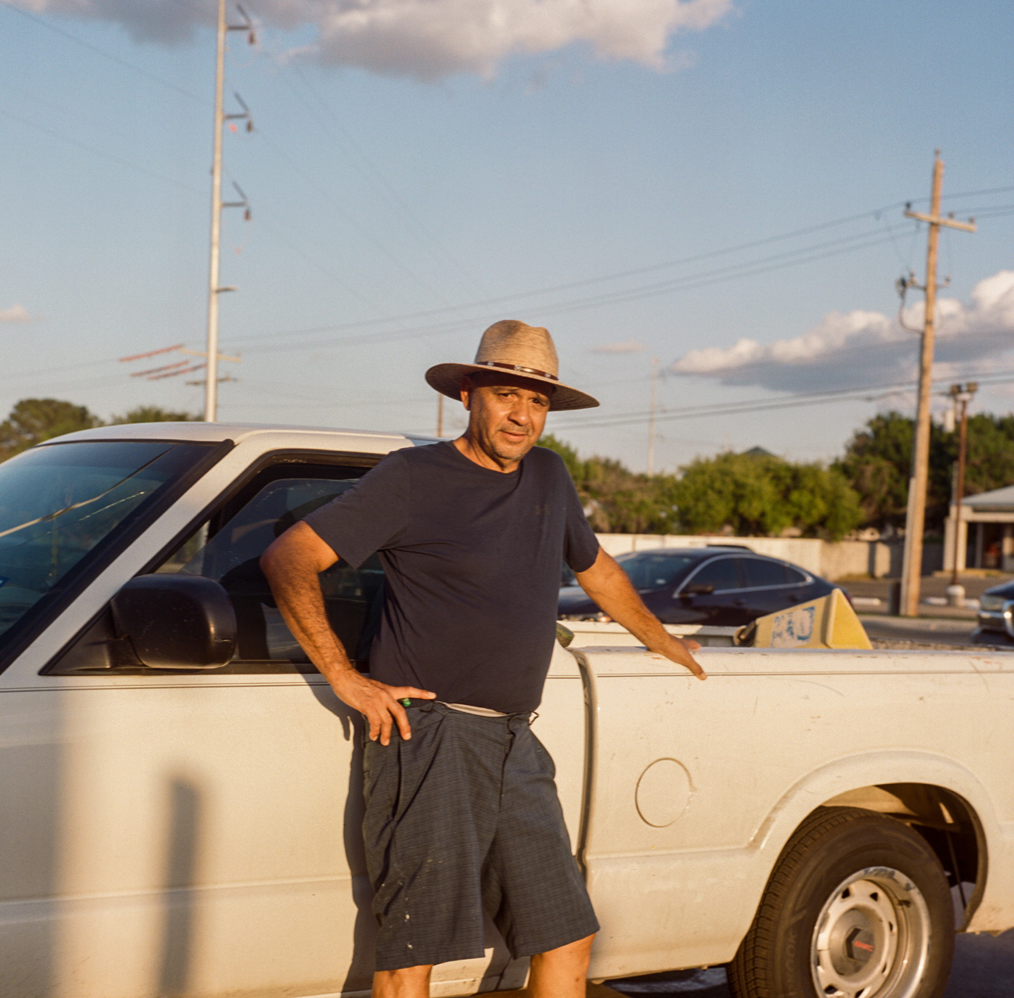 Portrait of man in a hat standing by a pick-up truck.