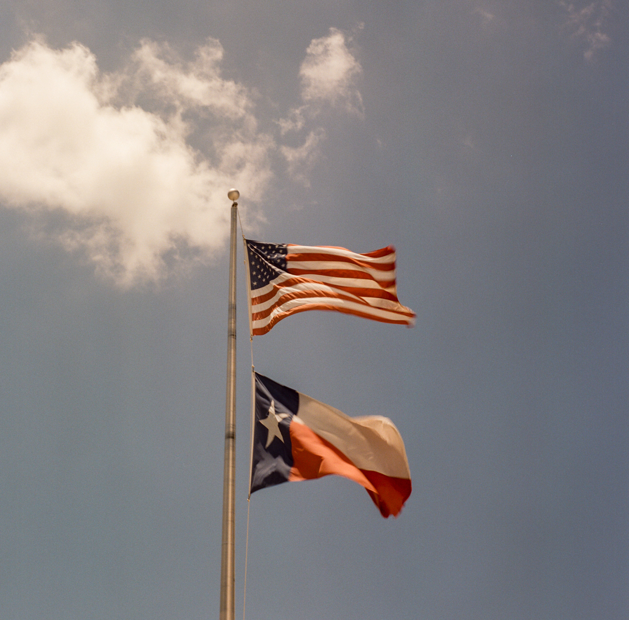 American and Texas flags flying on a flagpole.