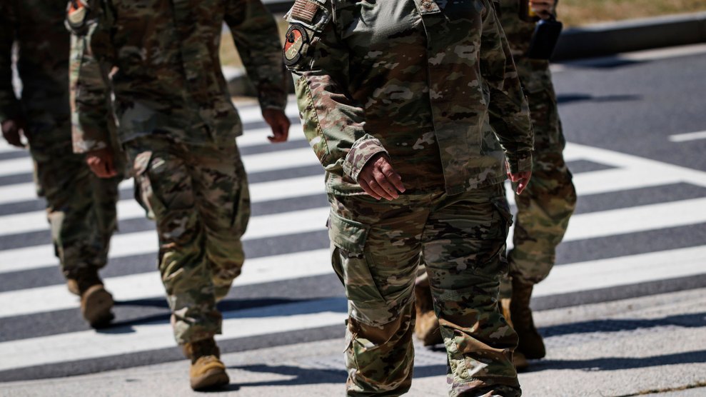 We see green-camoflaged bodies of National Guard personnel in a crosswalk. Their heads are not visible.