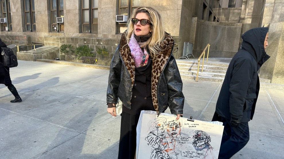 A woman with long hair, sunglasses, and a coat stands on a sidewalk in front of a building holding paper with her illustrations on it.