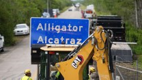 A worker placing the "Alligator Alcatraz" sign on July 3, 2025 at the entrance to the then-new migrant detention facility in Ochopee, Florida.