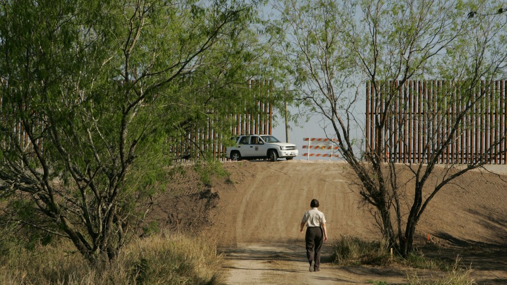 A person walks through the trees toward a wall.