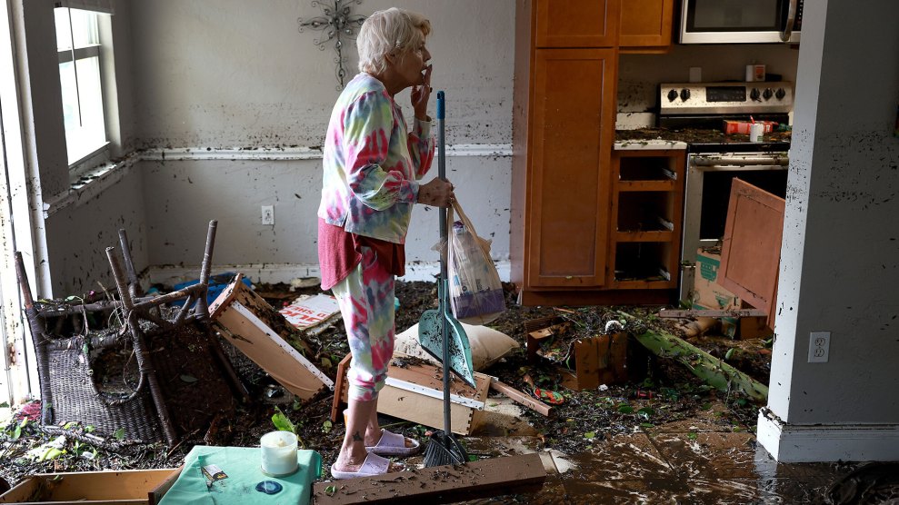 A woman stands in a damaged home.
