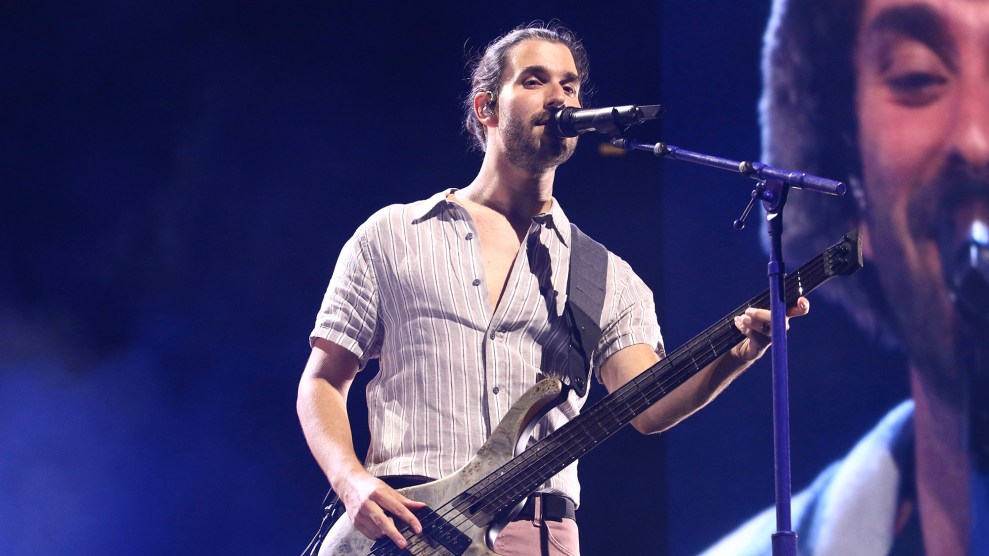 A man with long hair tied back plays the base.