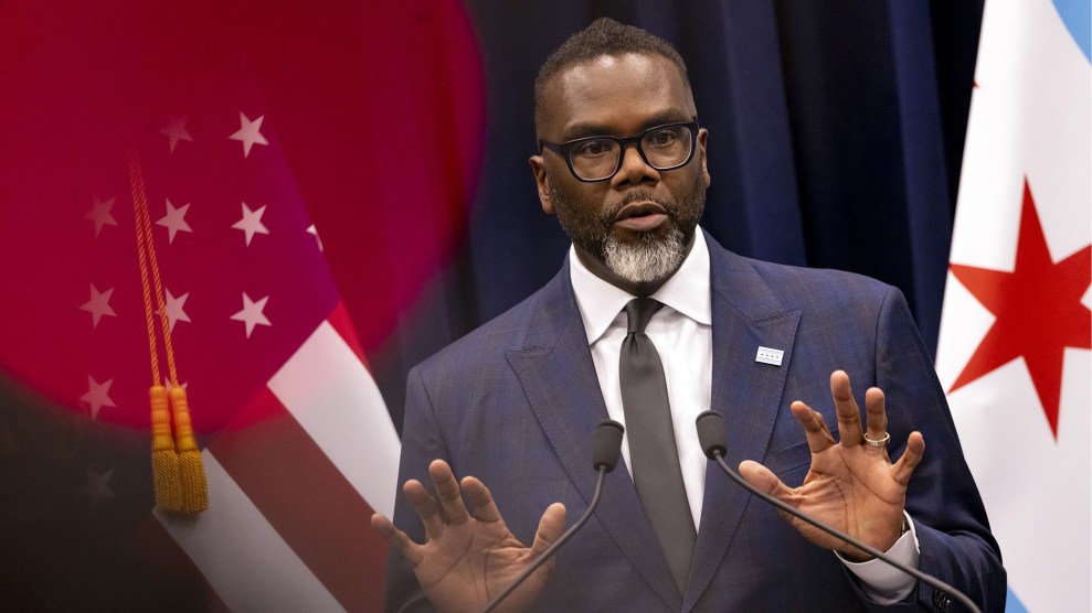 Mayor Brandon Johnson of Chicago standing between American flag and flag of Chicago.