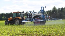 A farmer applies pesticides on a field with a tractor.