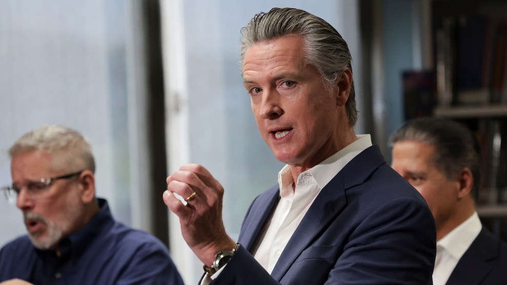 A white man holds up his hand as he speaks.