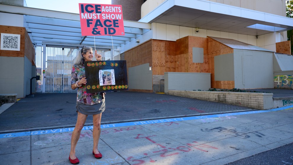 woman stands outside boarded up building with protest signs
