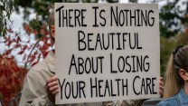 Someone holding up a sign that says "There is nothing beautiful about losing your health care"