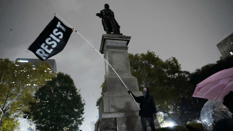 A protester waves a flag in a pouring rain during a demonstration against an impending Customs and Border Patrol immigration crackdown in New Orleans