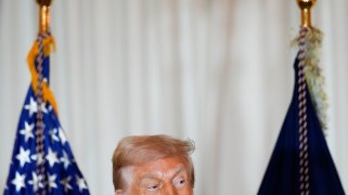 A photo of Donald Trump in front of two flags, with the bottom of the frame cutting off half his face