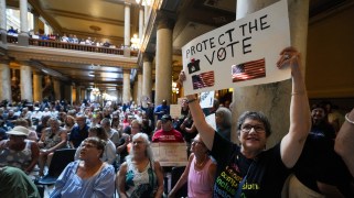 An opponent of gerrymandering in Indiana holds a sign saying protect the vote during a rally featuring former Transportation Secretary Pete Buttigieg