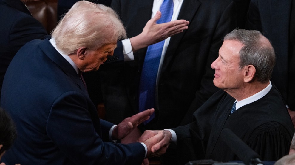 Donald Trump, in a blue suit, left, shakes hands with John Roberts, a gray-haired white man in a black suit and robes.
