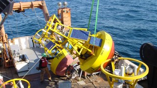 A ship deck with a large, yellow, solar-powered buoy on it.