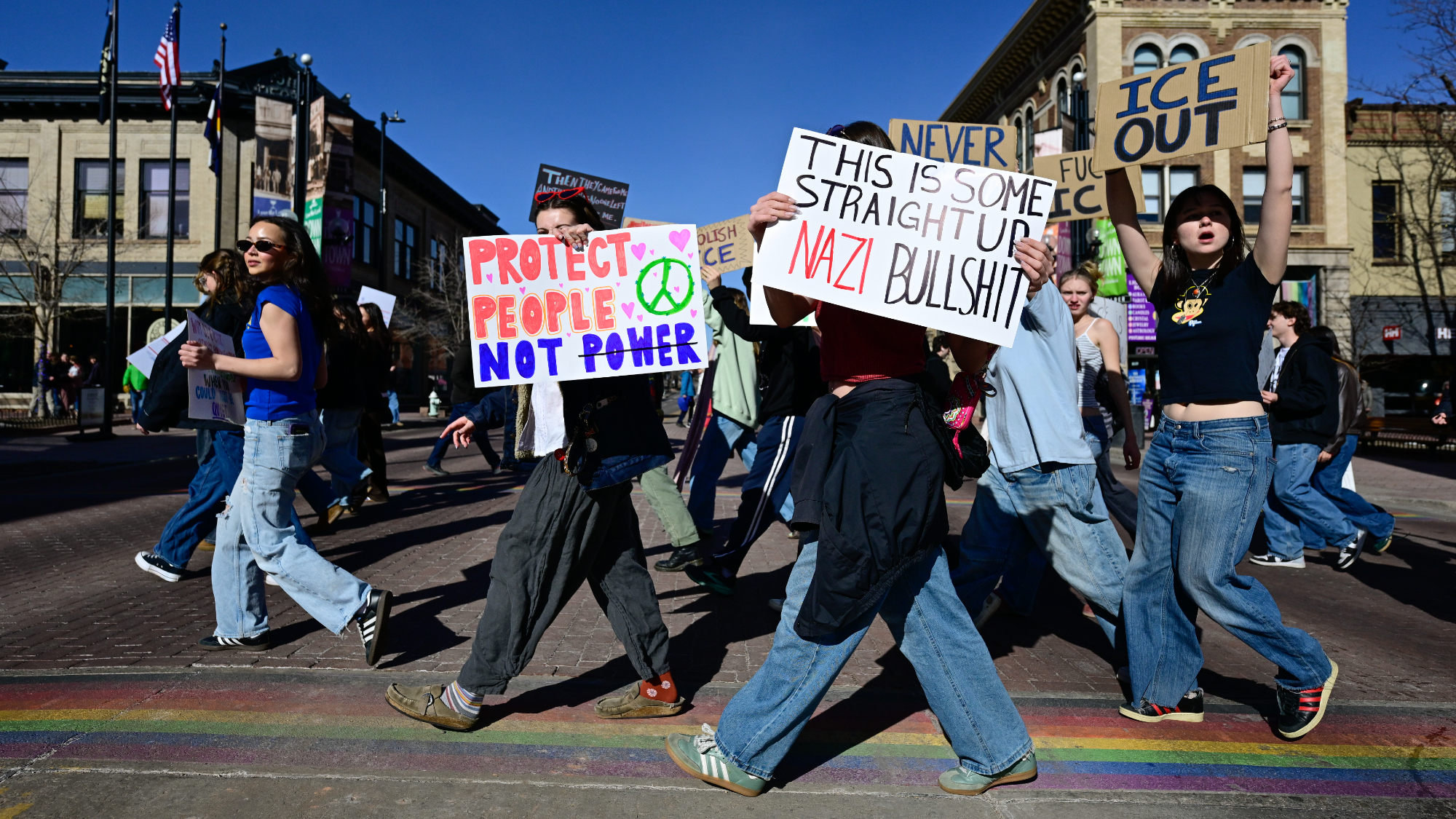 A group of protesters cross Broadway while marching on the Pearl Street Mall during a general strike solidarity protest in Boulder on Friday, Jan. 30, 2026. One sign says "THIS IS SOME STRAIGHT UP NAZI BULLSHIT."