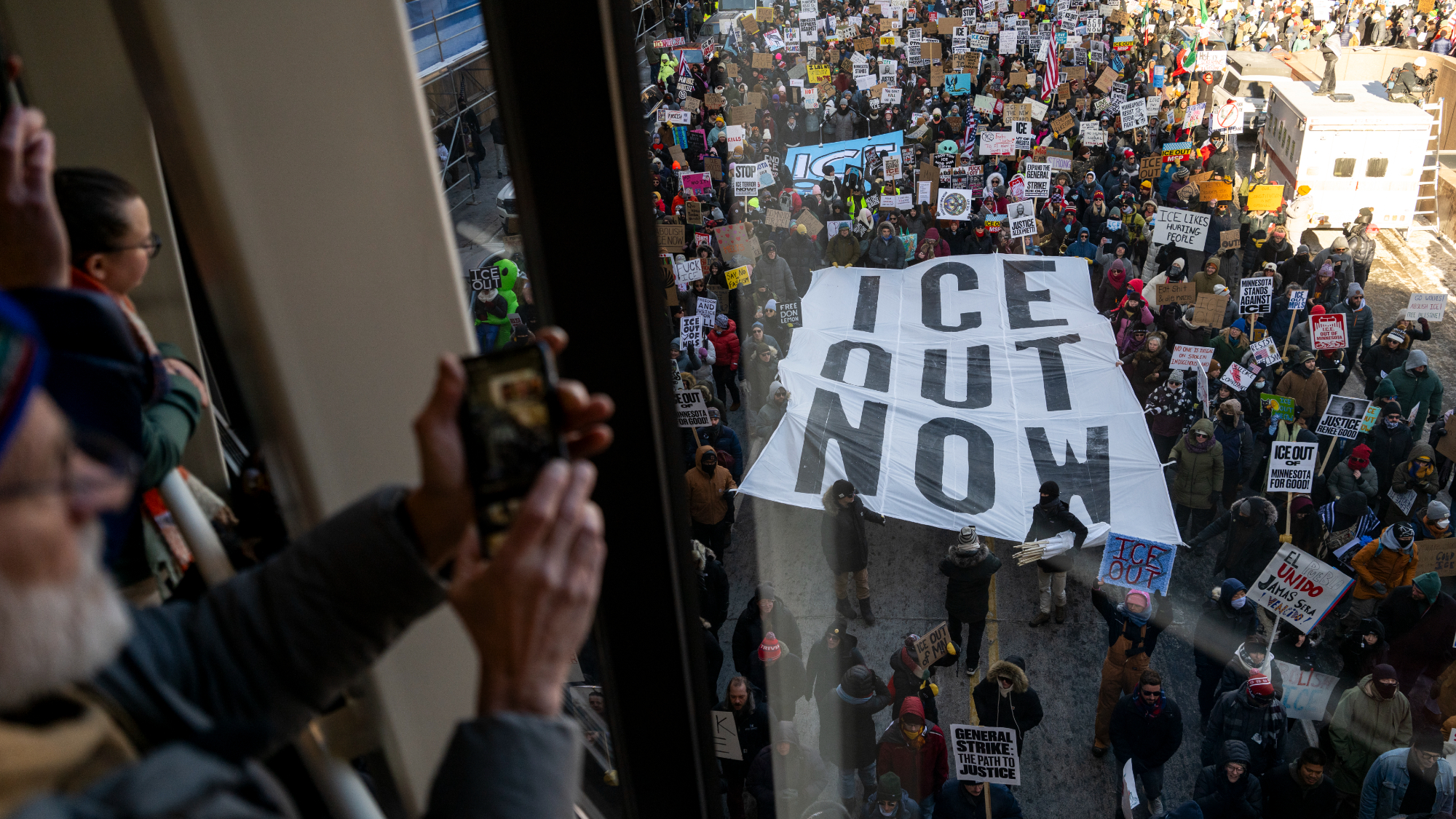 People look on from a skyway as demonstrators march during a "Nationwide Shutdown" demonstration against ICE enforcement on January 30, 2026 in Minneapolis, Minnesota. 