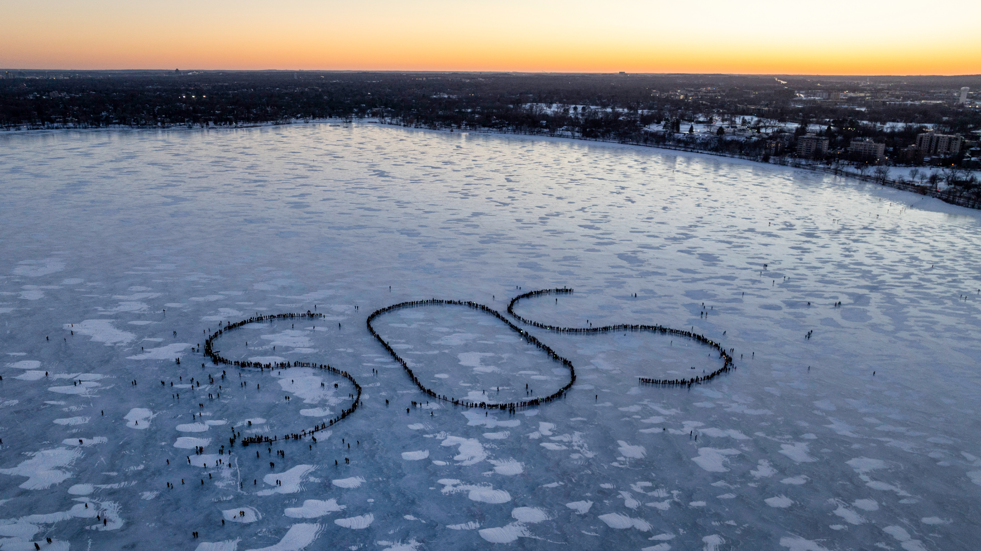 In an aerial view, demonstrators spell out an SOS signal of distress on a frozen Lake BdeMaka Ska on January 30, 2026 in Minneapolis, Minnesota.