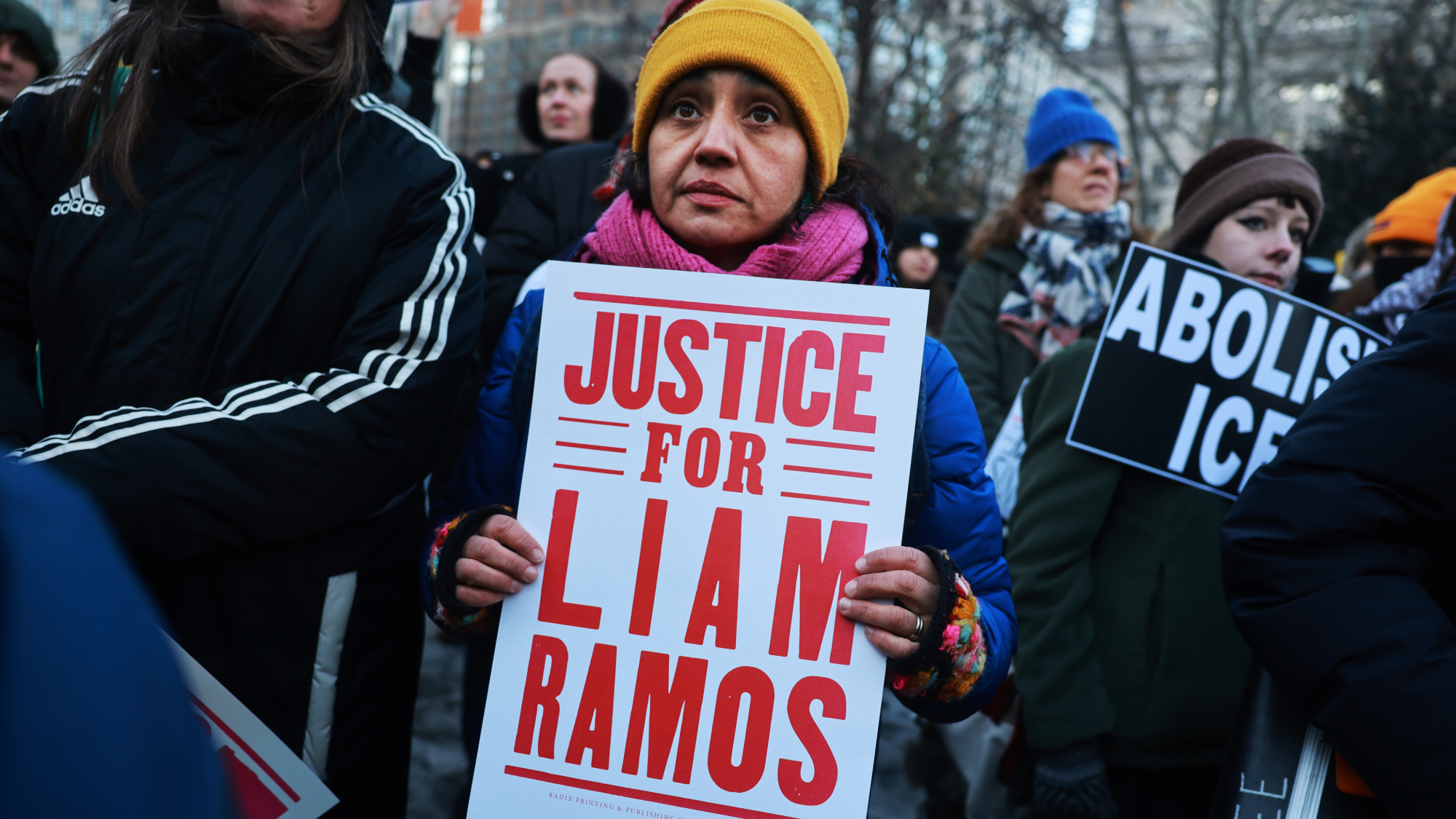 A woman holds up a sign reading "JUSTICE FOR LIAM RAMOS."