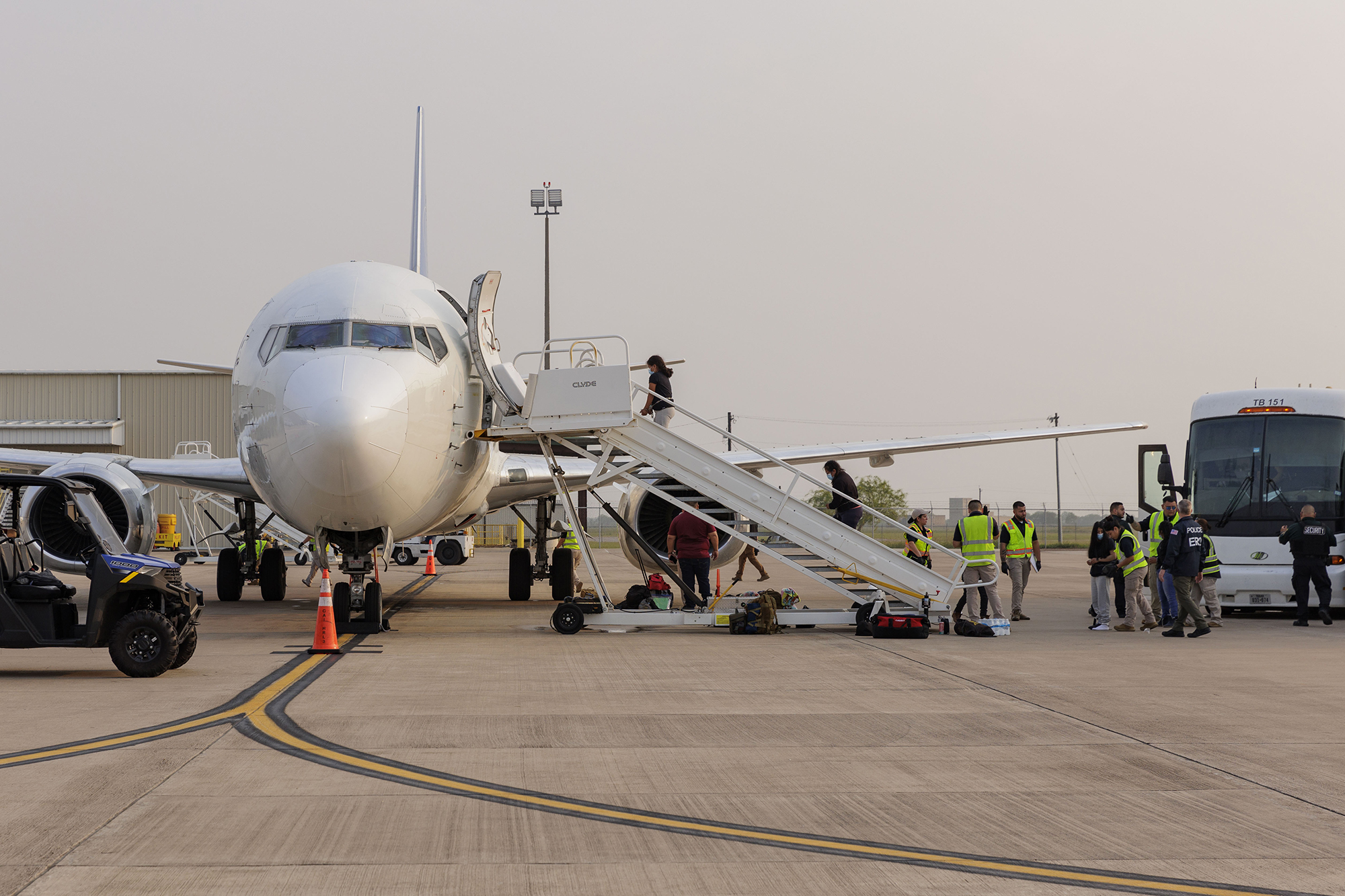 Shackled migrants board an aircraft, as seen from the tarmac. 