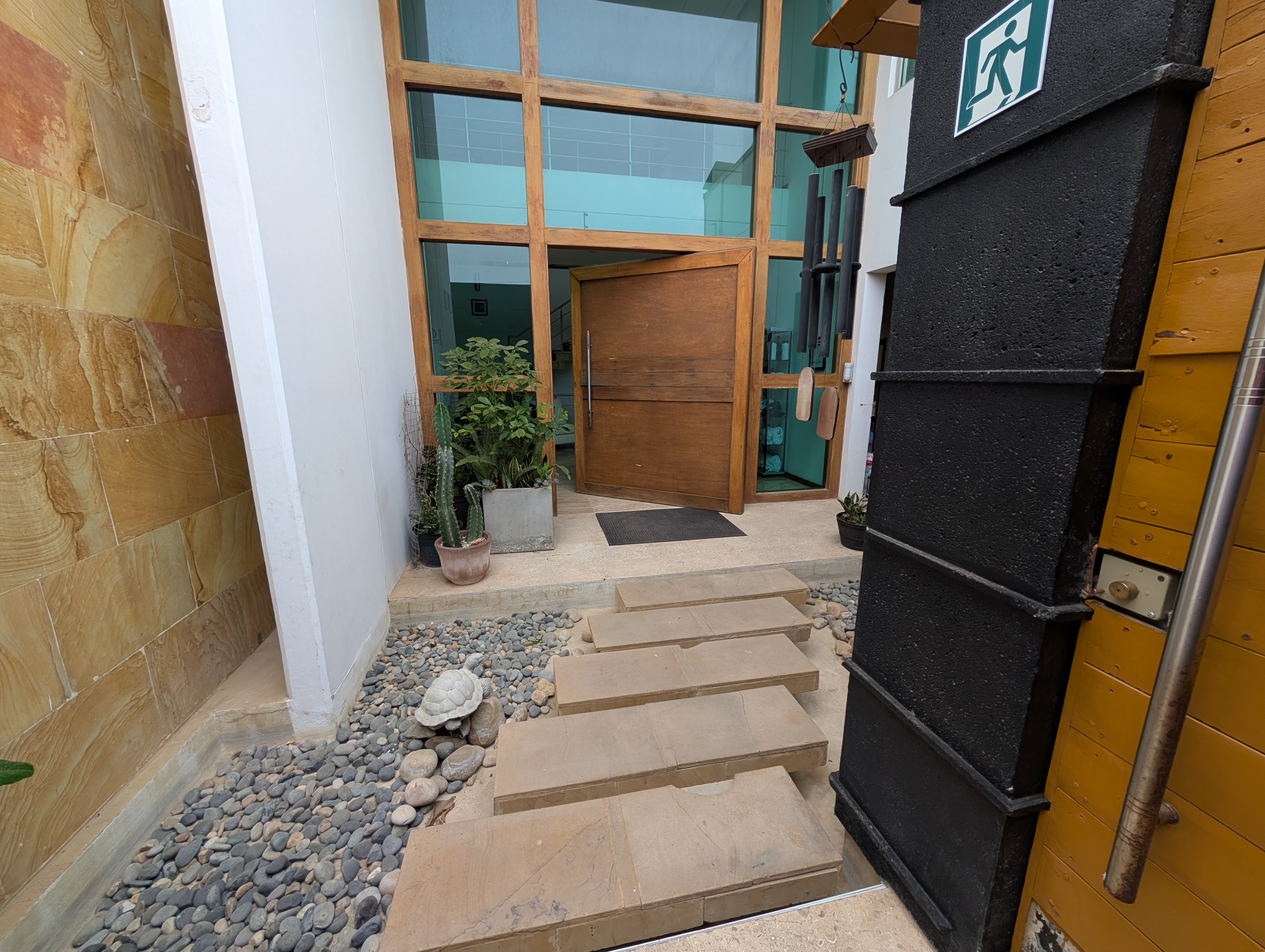 A large entry way into a chic looking building with a wide wooden door.