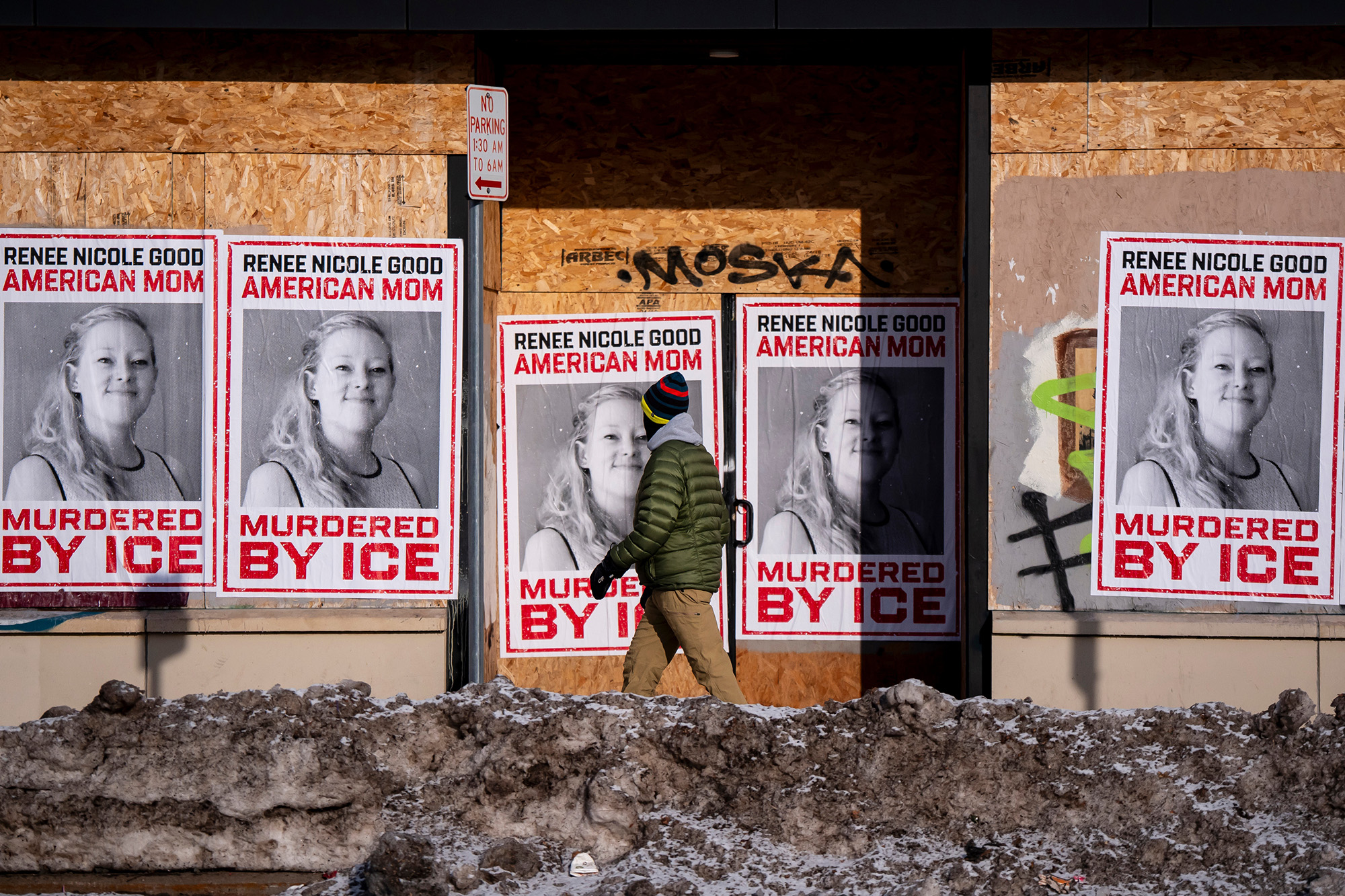 Person walks past large posters featuring Renee Good.