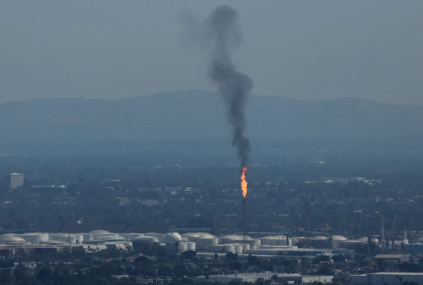 A burning smokestack over a city
