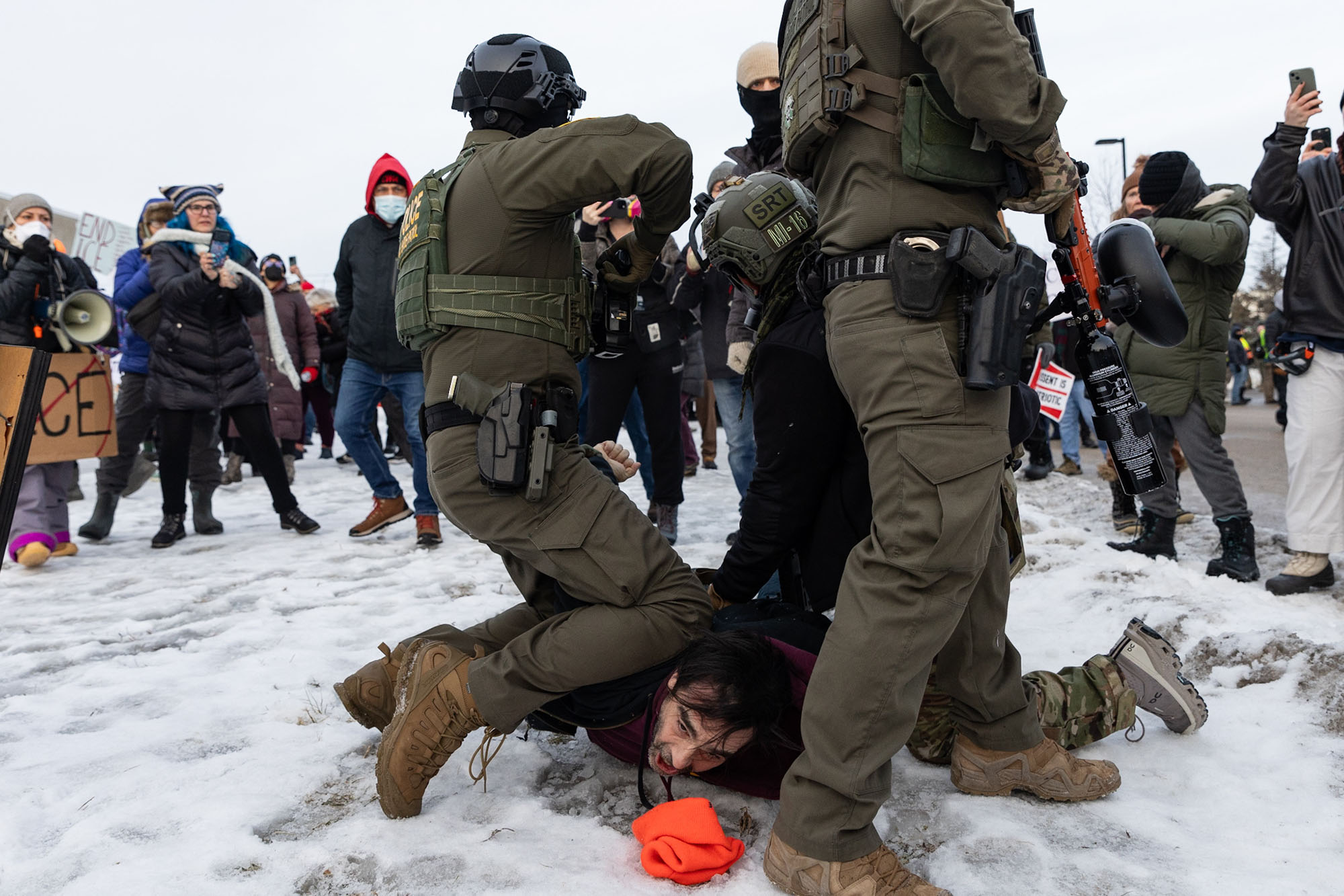Federal agents wrestle a man to the ground in the snow.