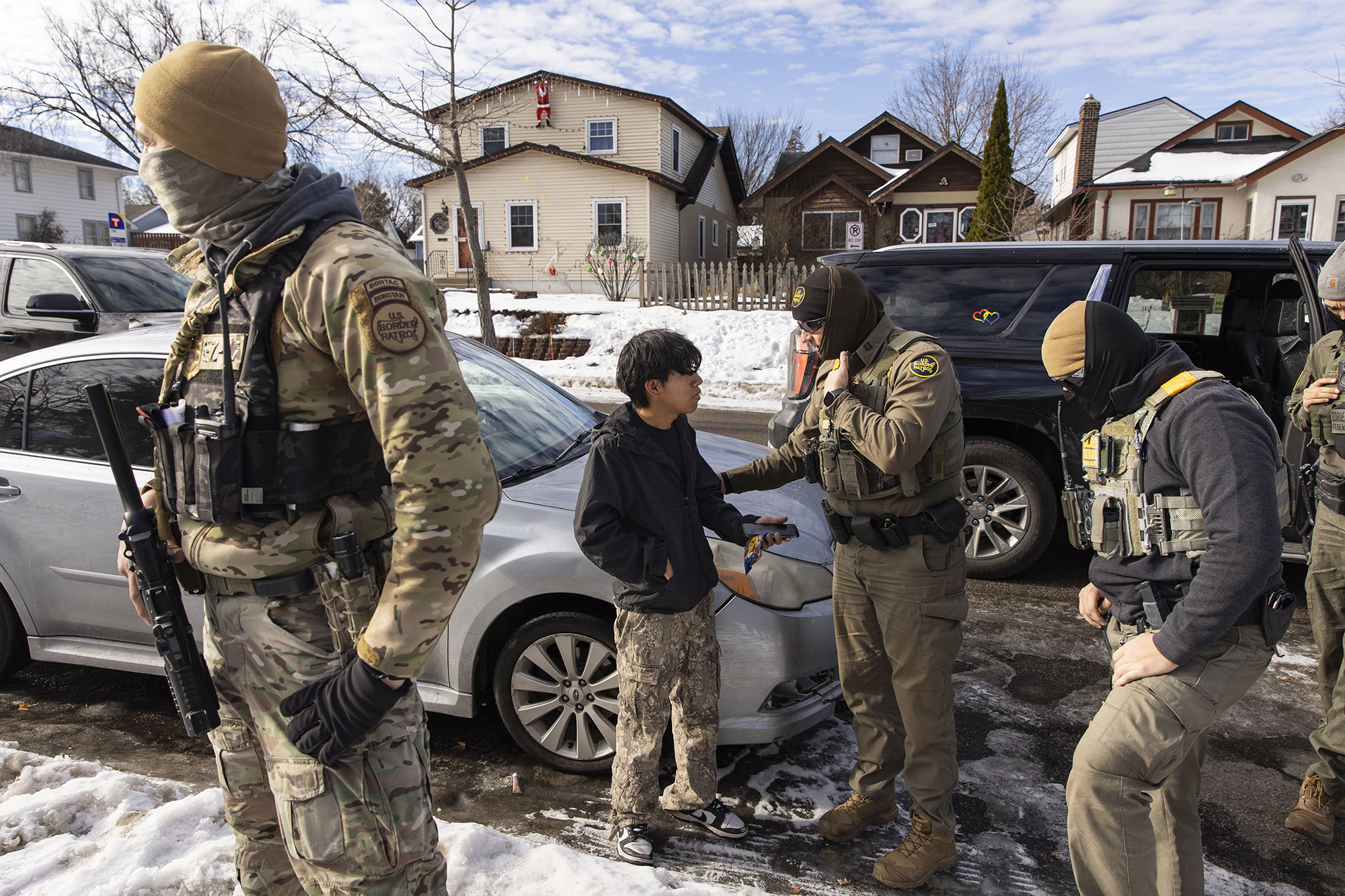Border Patrol agents surround a young boy as another agent talks to him.