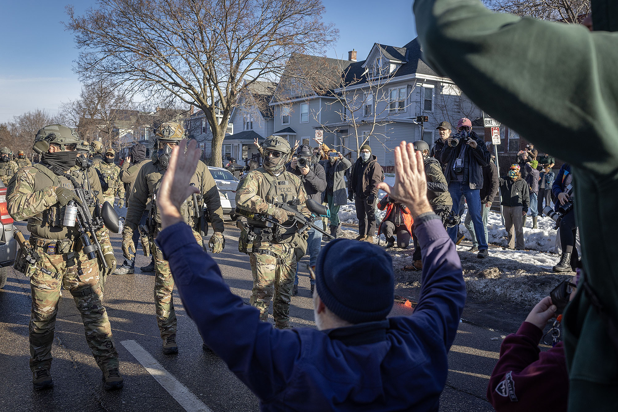 People with their hands up face off against a line of federal agents in camouflage.