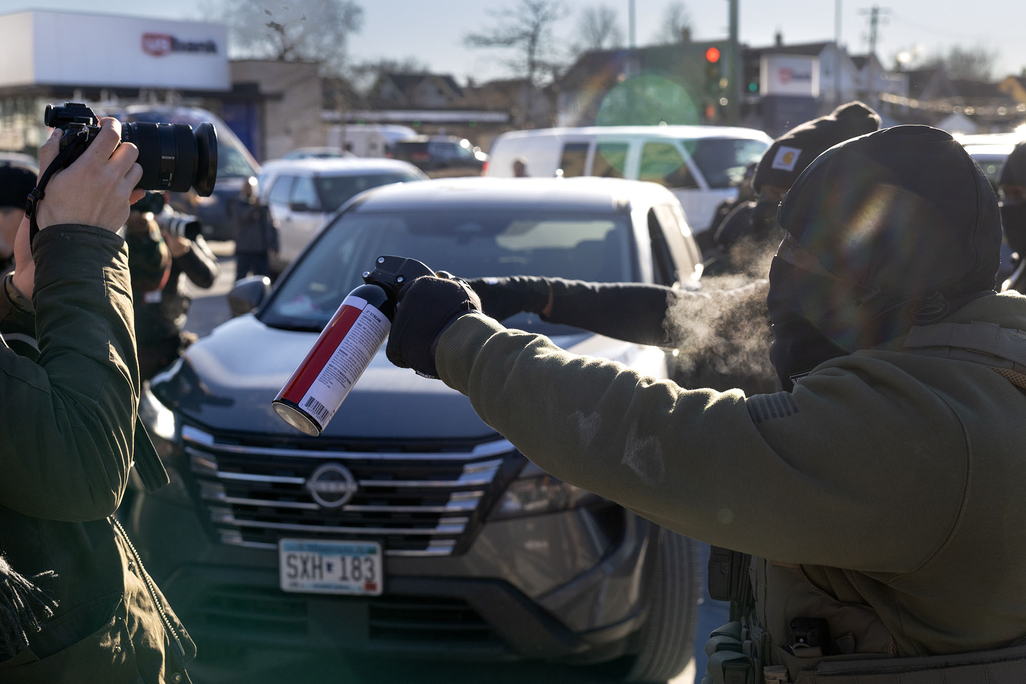A federal agent holds a tear gas canister in front of a photographer.