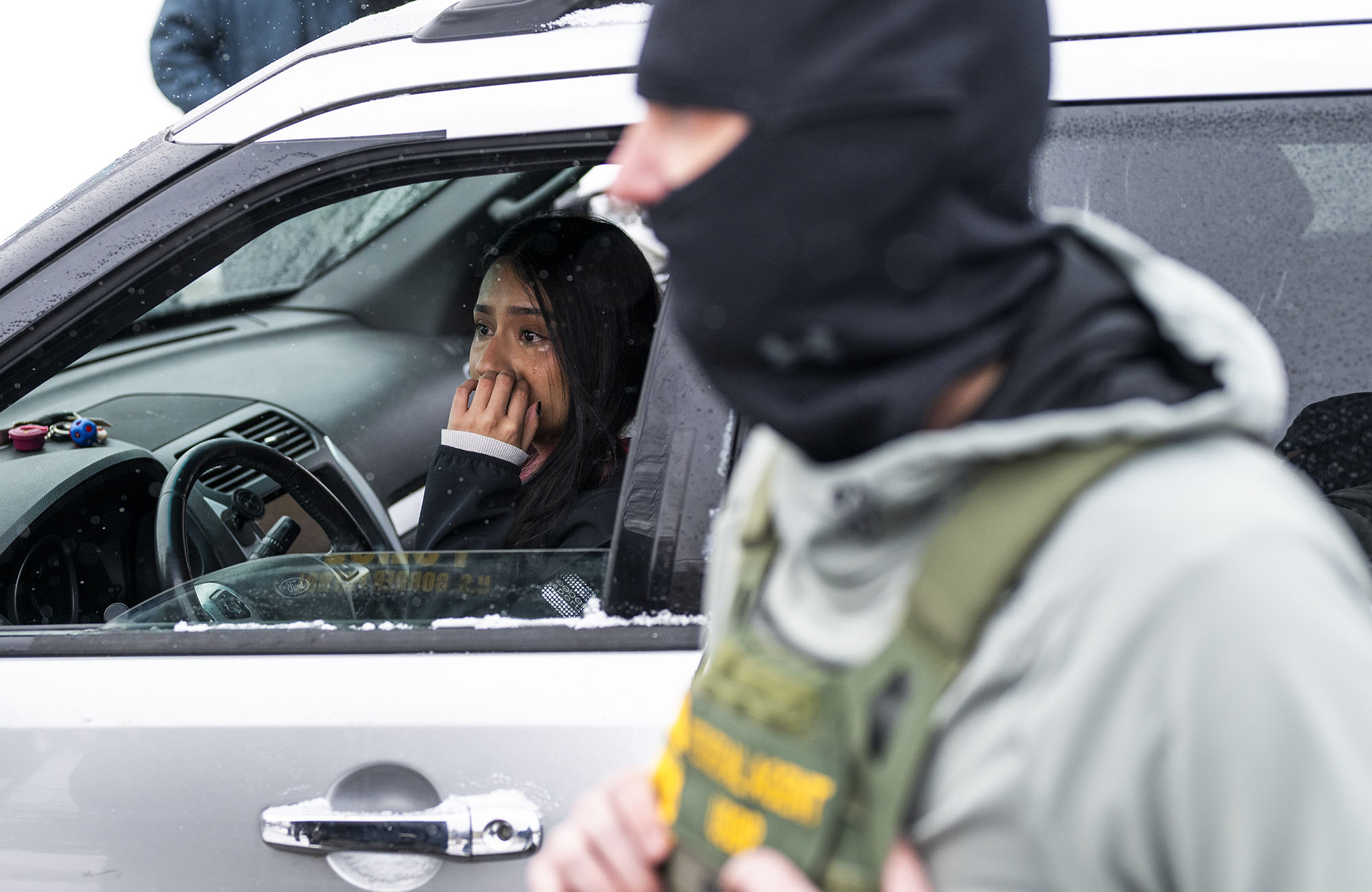A frightened woman sits in her car with the window down.