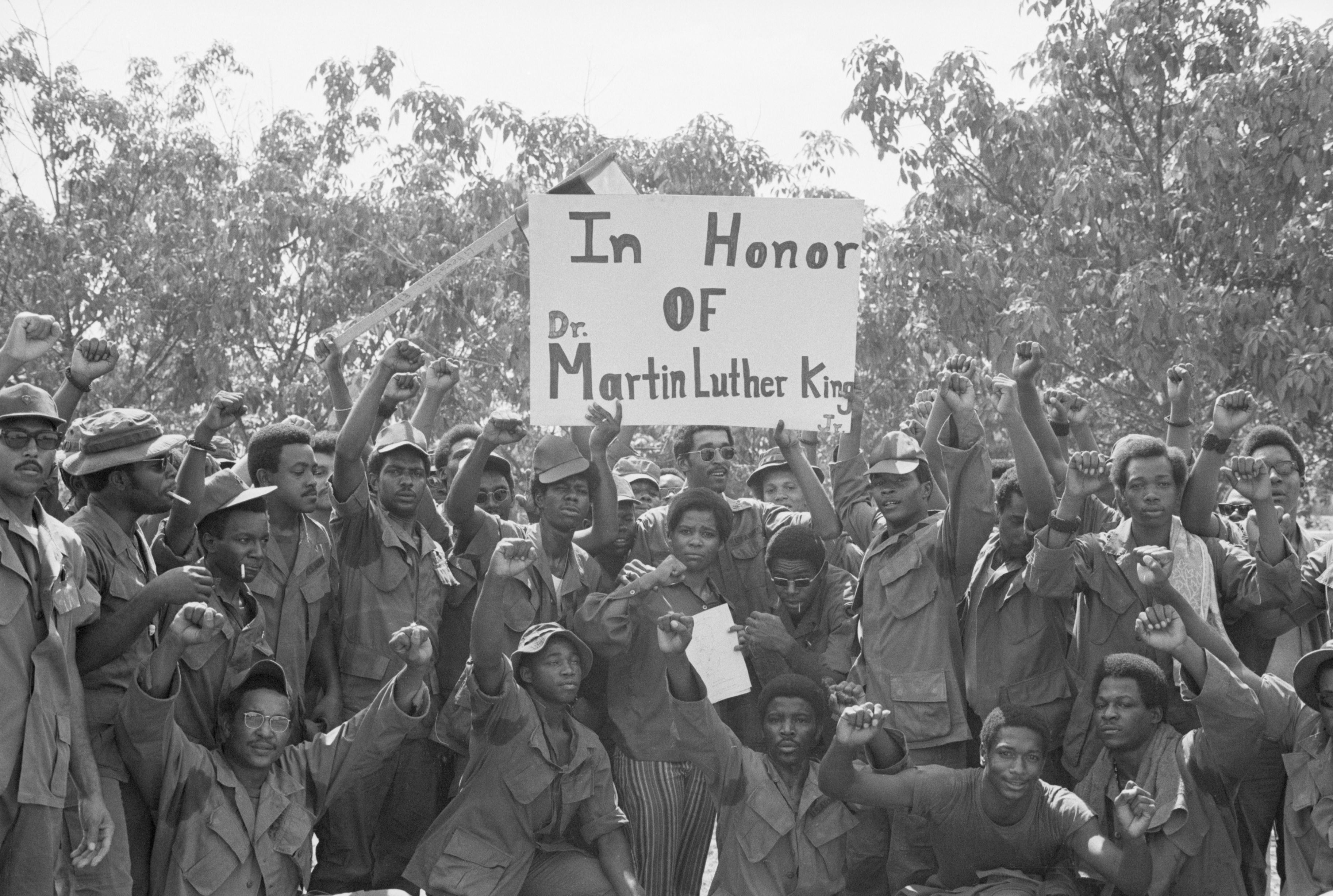 Group of black soldiers in Vietnam hold up a sign that reads, "In Honor of Dr. Martin Luther King."