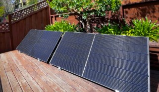 A solar panel on a deck, propped next to an elevated garden bed.