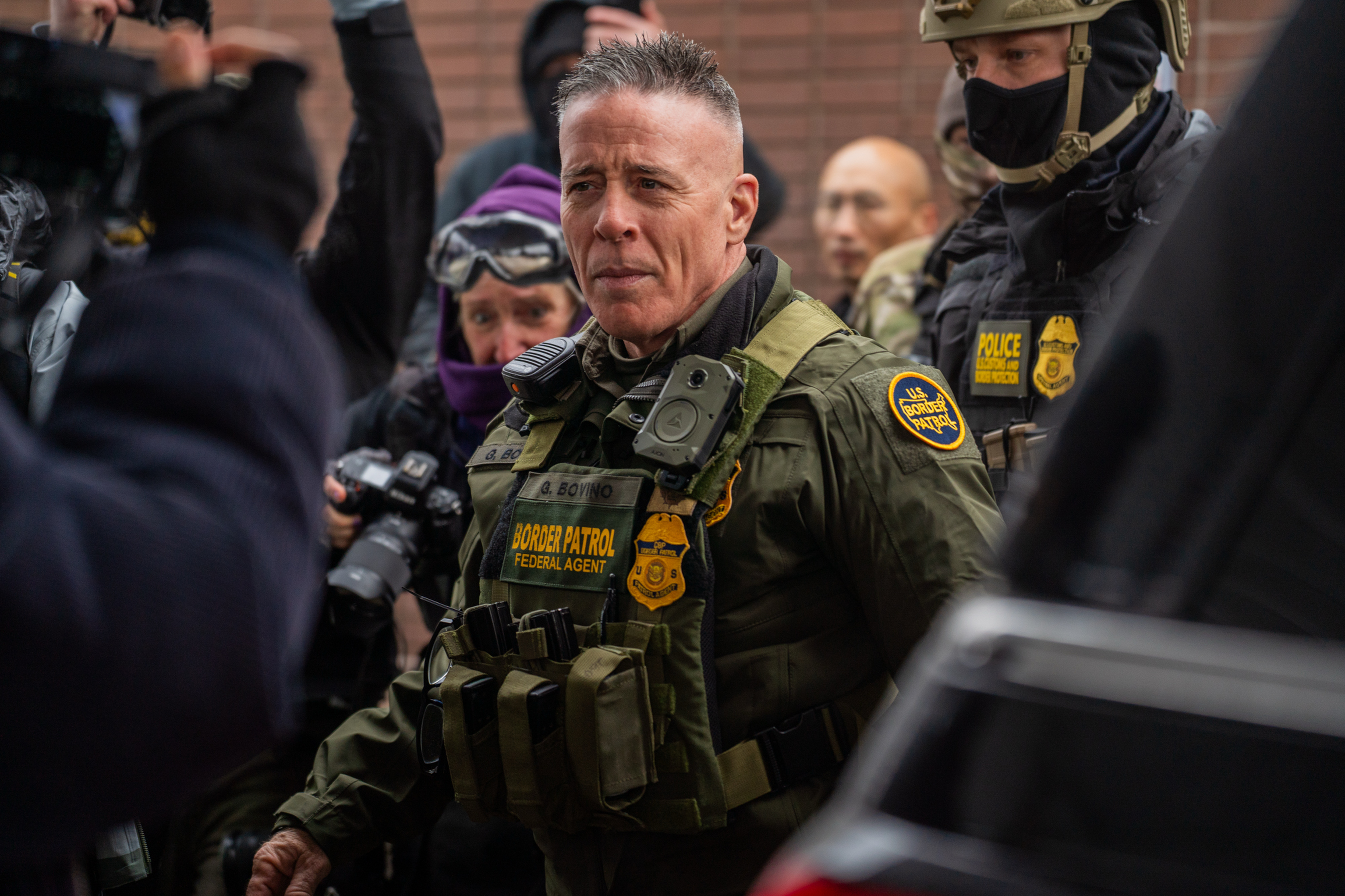 Man in camouflage and a military vest surrounded by federal agents.