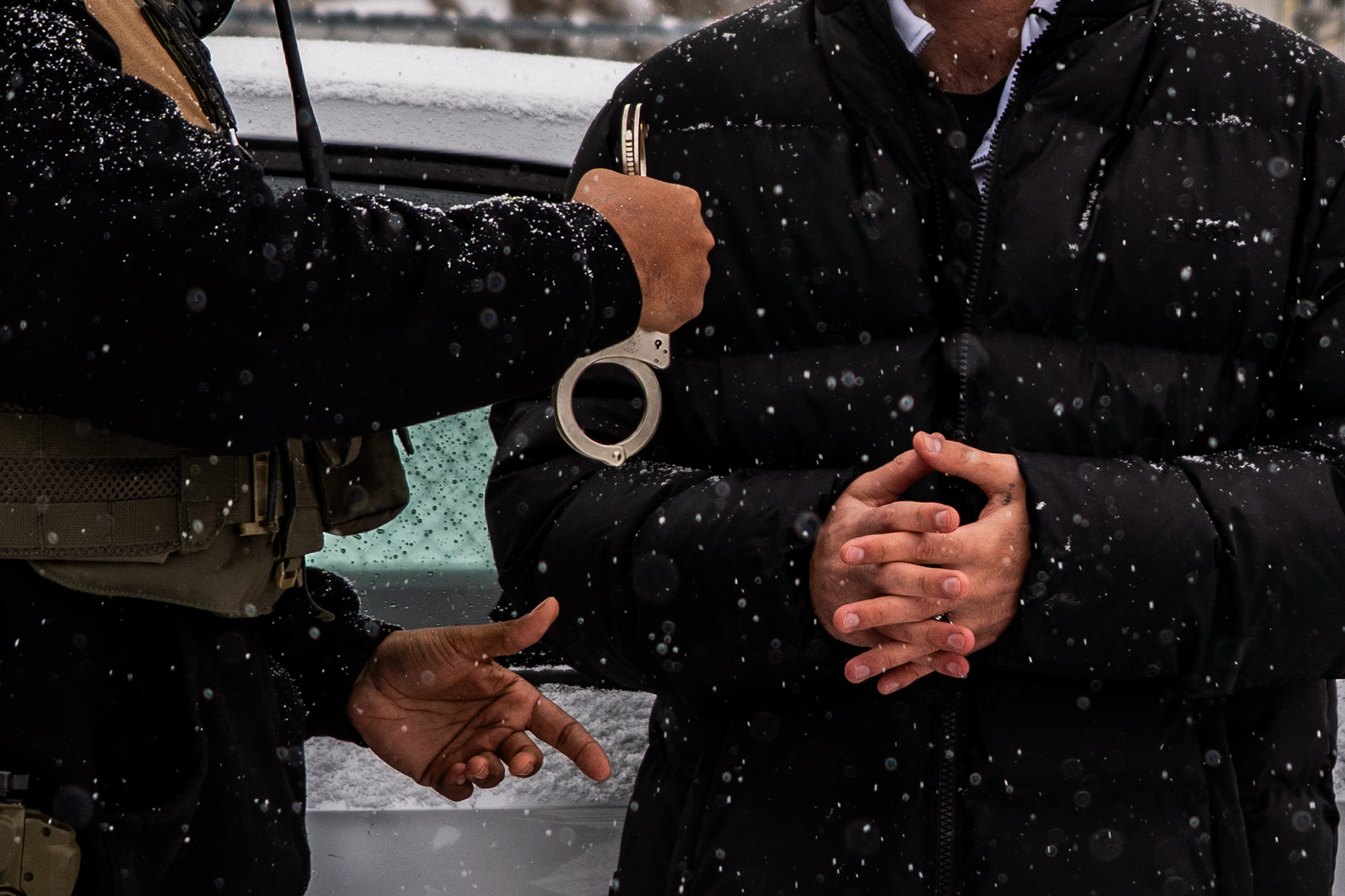 Close up of a man being handcuffed in the snow.