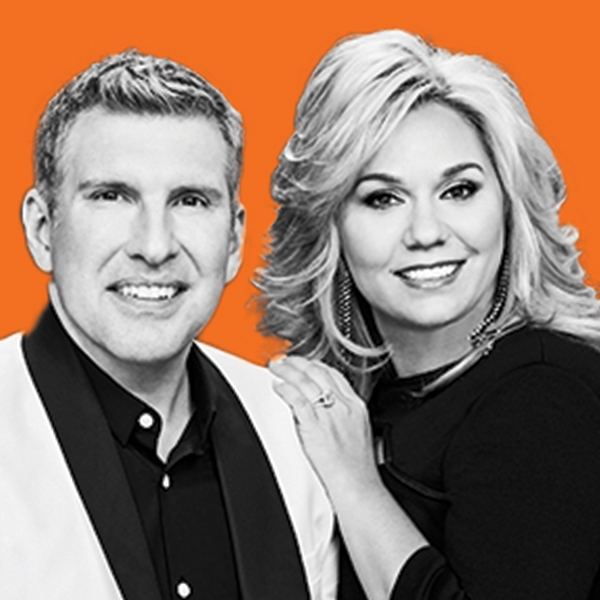 A white middle-aged couple smiling at the camera; they are dressed in business attire and the woman has her hand on the man's shoulder. 