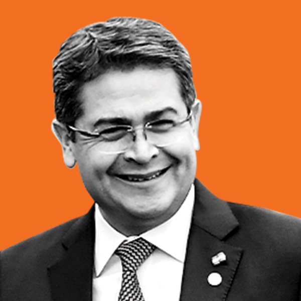 A bespectacled smiling man wearing a suit and tie. 