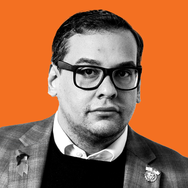 A bespectacled man in a checkered suit coat and dress clothes. 