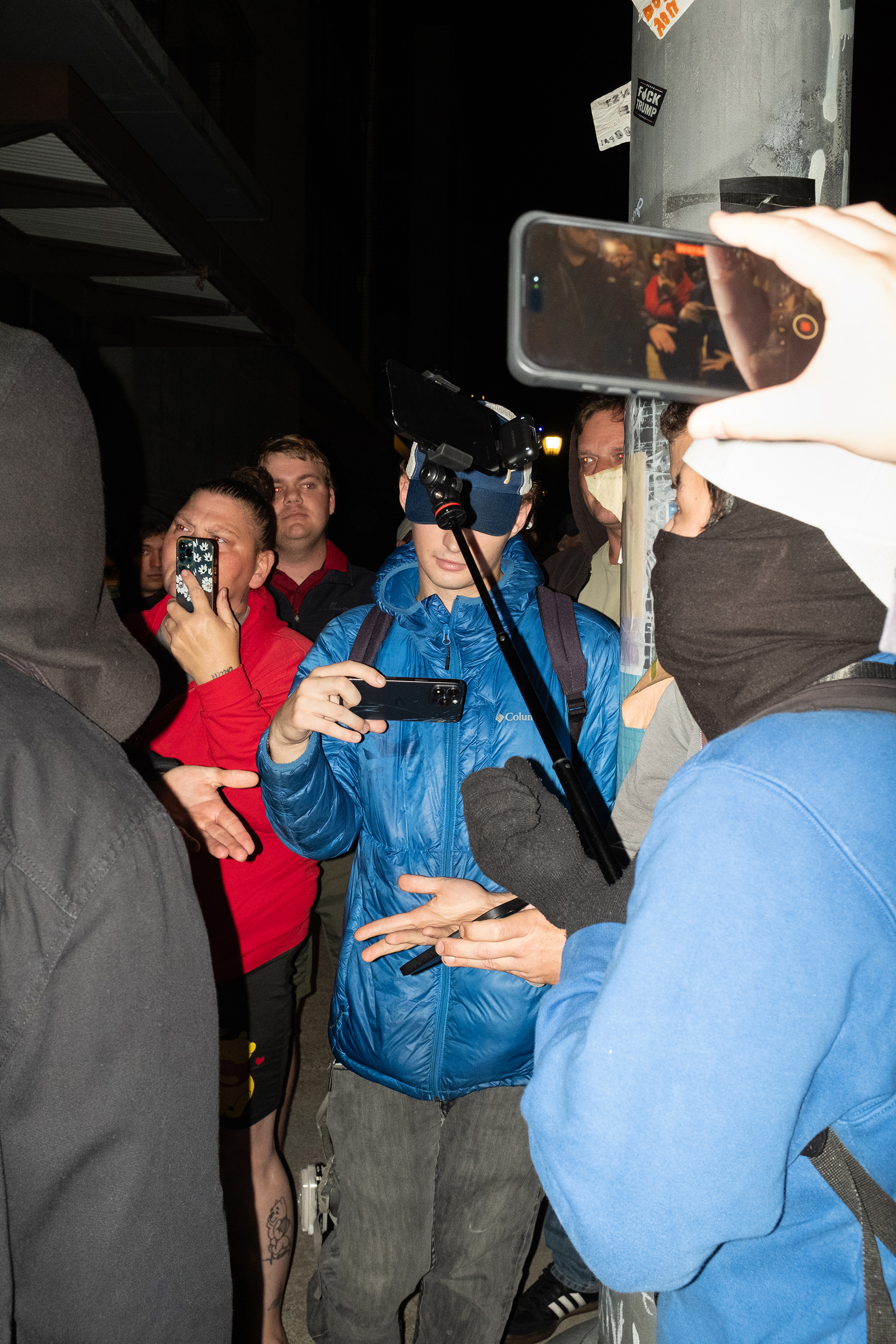 Numerous people holding cellphones at a protest.