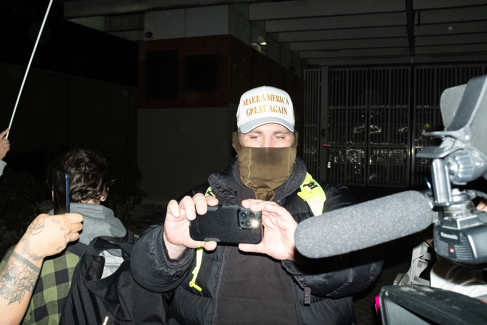 Man wearing a Make America Great Again hat with a cellphone.