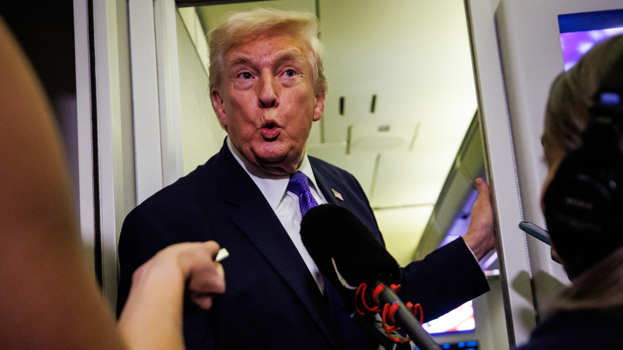 Trump is seen with his mouth slightly open as reporters put microphones near his face on Air Force One.