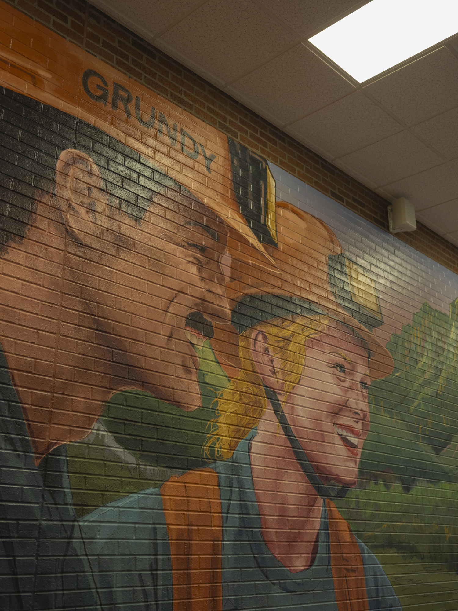 Mural of a man and woman as miners, both smiling, wearing yellow hard hats.