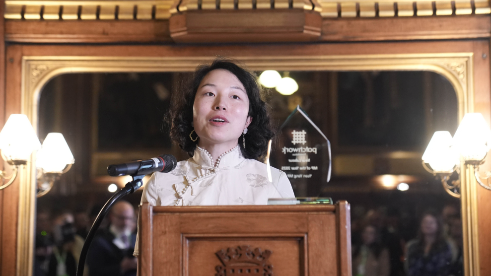 An Asian woman stands in front of a lectern.