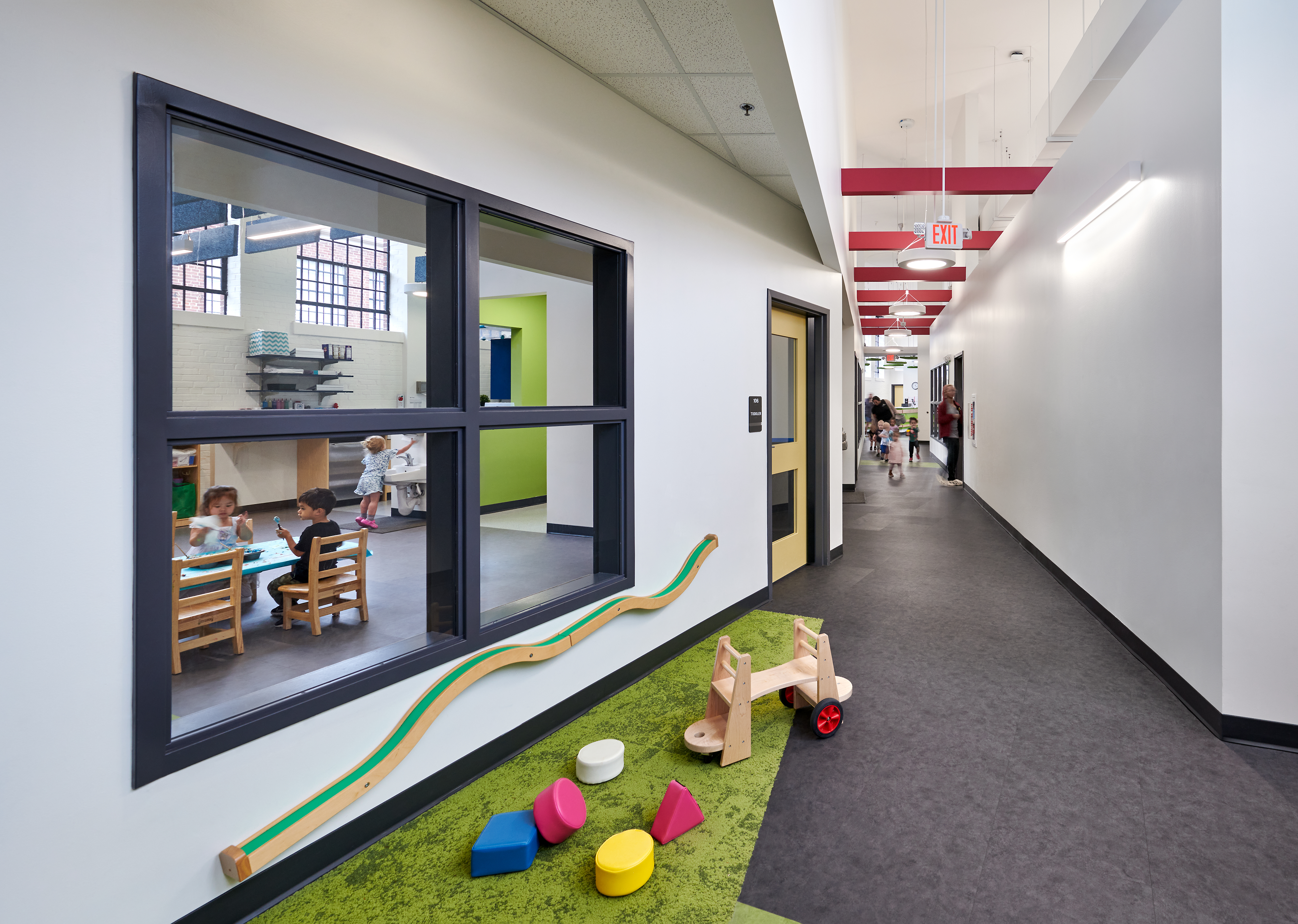 A hallway inside the Brynmor Early Education & Preschool. What was once a warehouse-like space now has rooms with tall square windows to look inside.