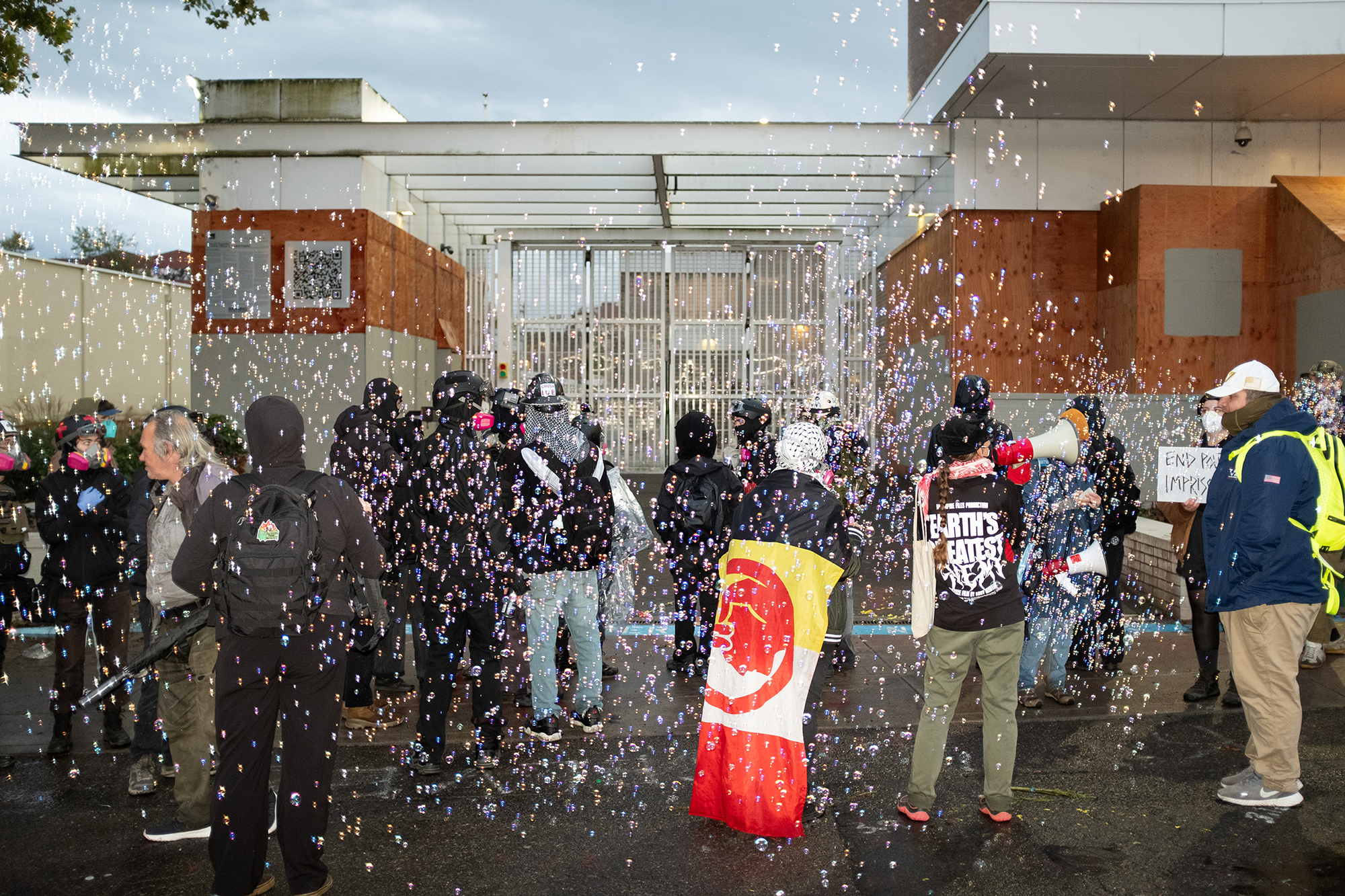 Crowd of protesters standing in front of a building among a number of bubbles.