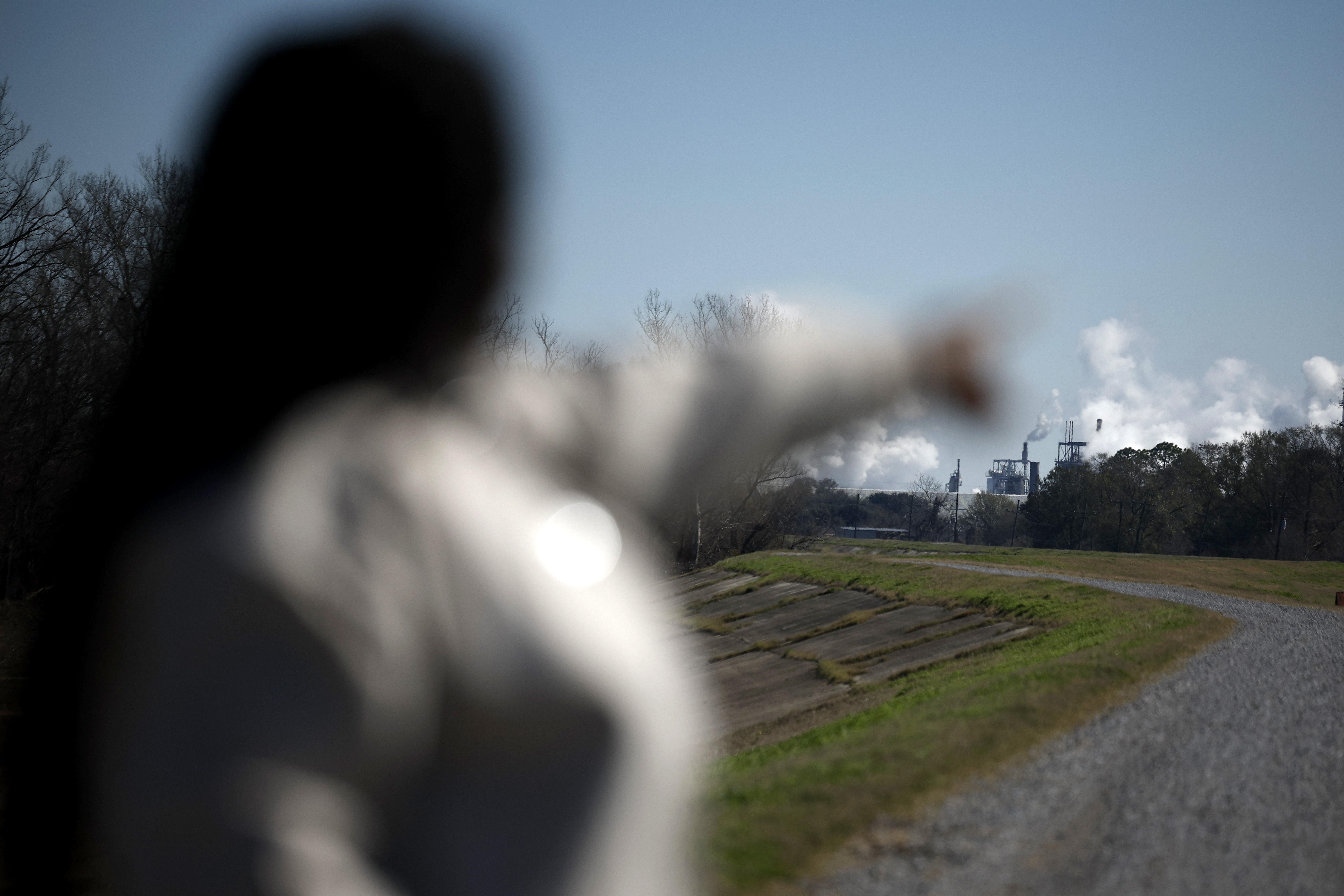 Ashley Gaignard stands outside pointing to pollution in the distance.